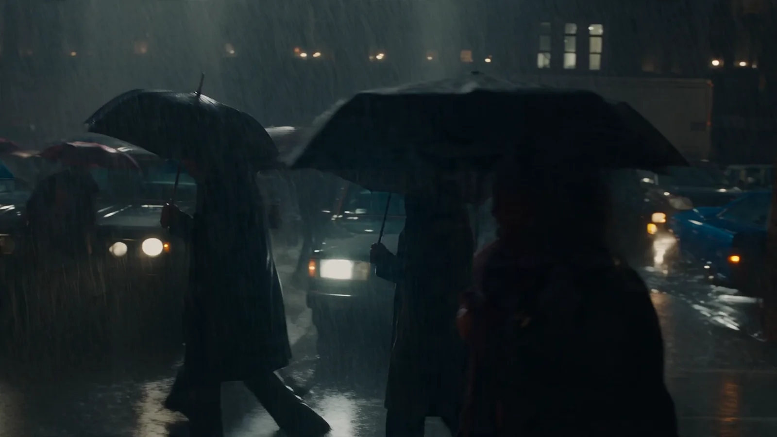 A crowd moves through heavy rain on a London street